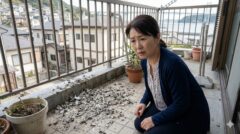 下関市の一軒家のベランダに溜まった乾燥したハトのフンと、それを心配そうに見つめる日本人女性。