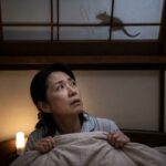 夜中、天井裏の気配に不安を感じて見上げる日本の女性