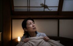 夜中、天井裏の気配に不安を感じて見上げる日本の女性