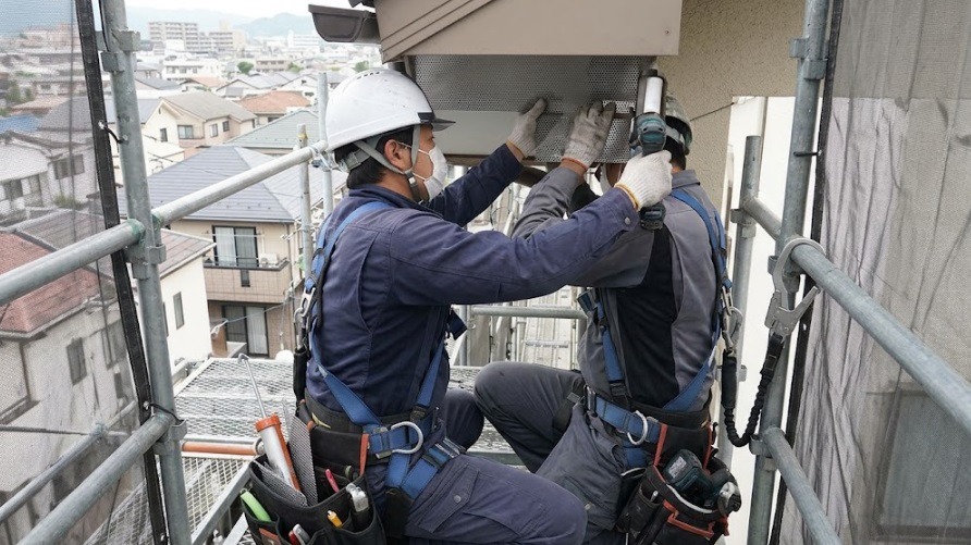 安全帯(ハーネス)を着用し、高所の足場から住宅の軒下の隙間に金網を取り付けて侵入口を完全に封鎖するプロの駆除業者